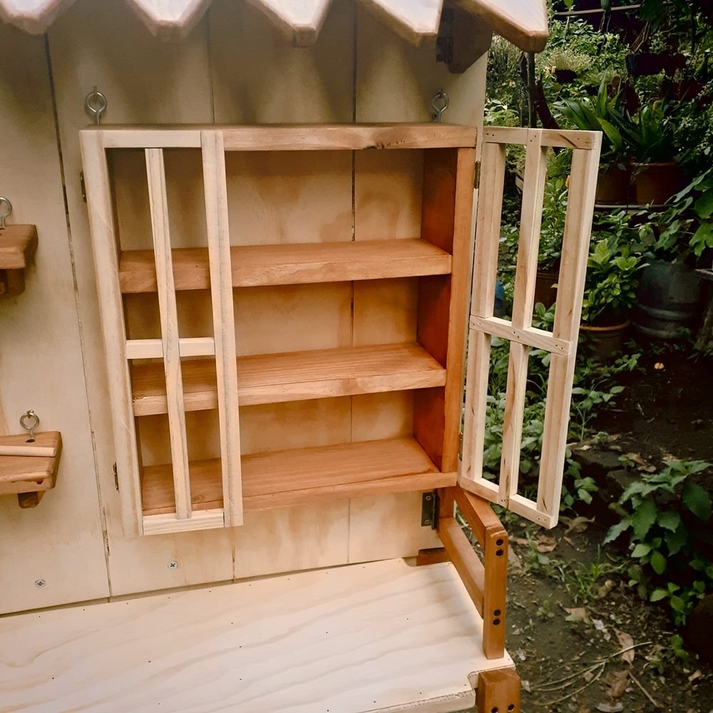 Detalle de la vitrina de madera con una puerta de celosía abierta y tres repisas