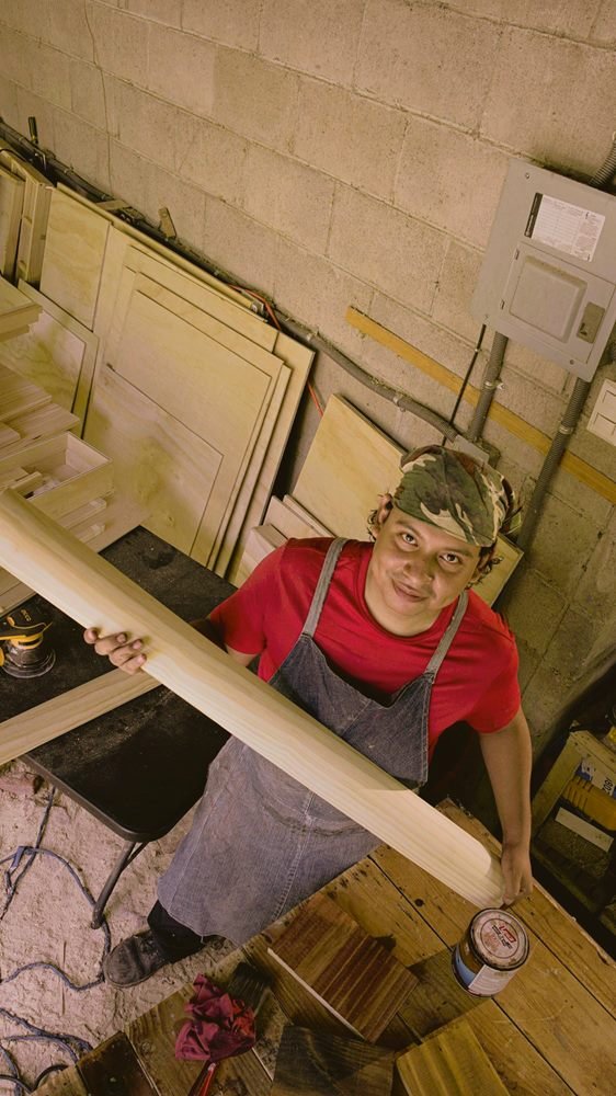 Integrante de IDEOMOV sosteniendo un tablón de pino en el taller